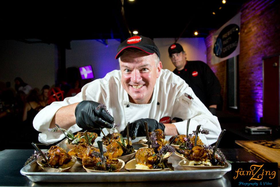 Peter Collins smiling with plated meals at event